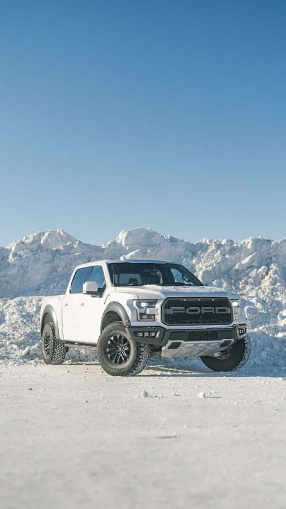 a white truck parked on top of a snow covered field